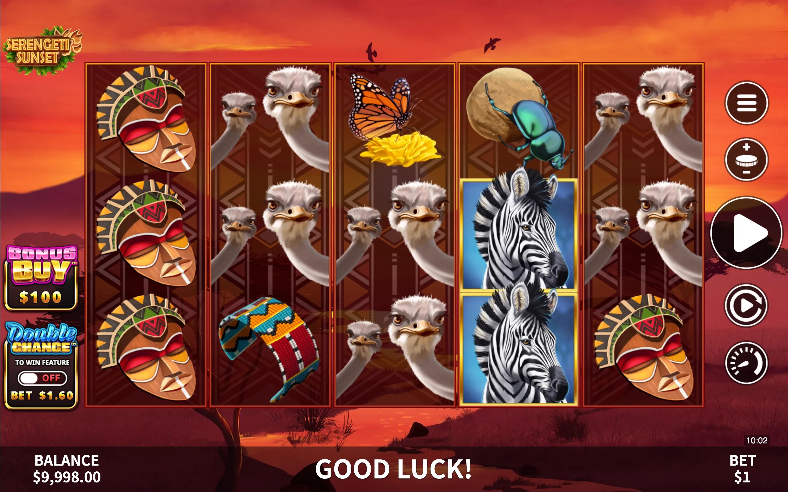 Slot game Serengeti Sunset features African wildlife symbols including ostriches, zebras, tribal masks, and insects against a warm orange sunset backdrop.