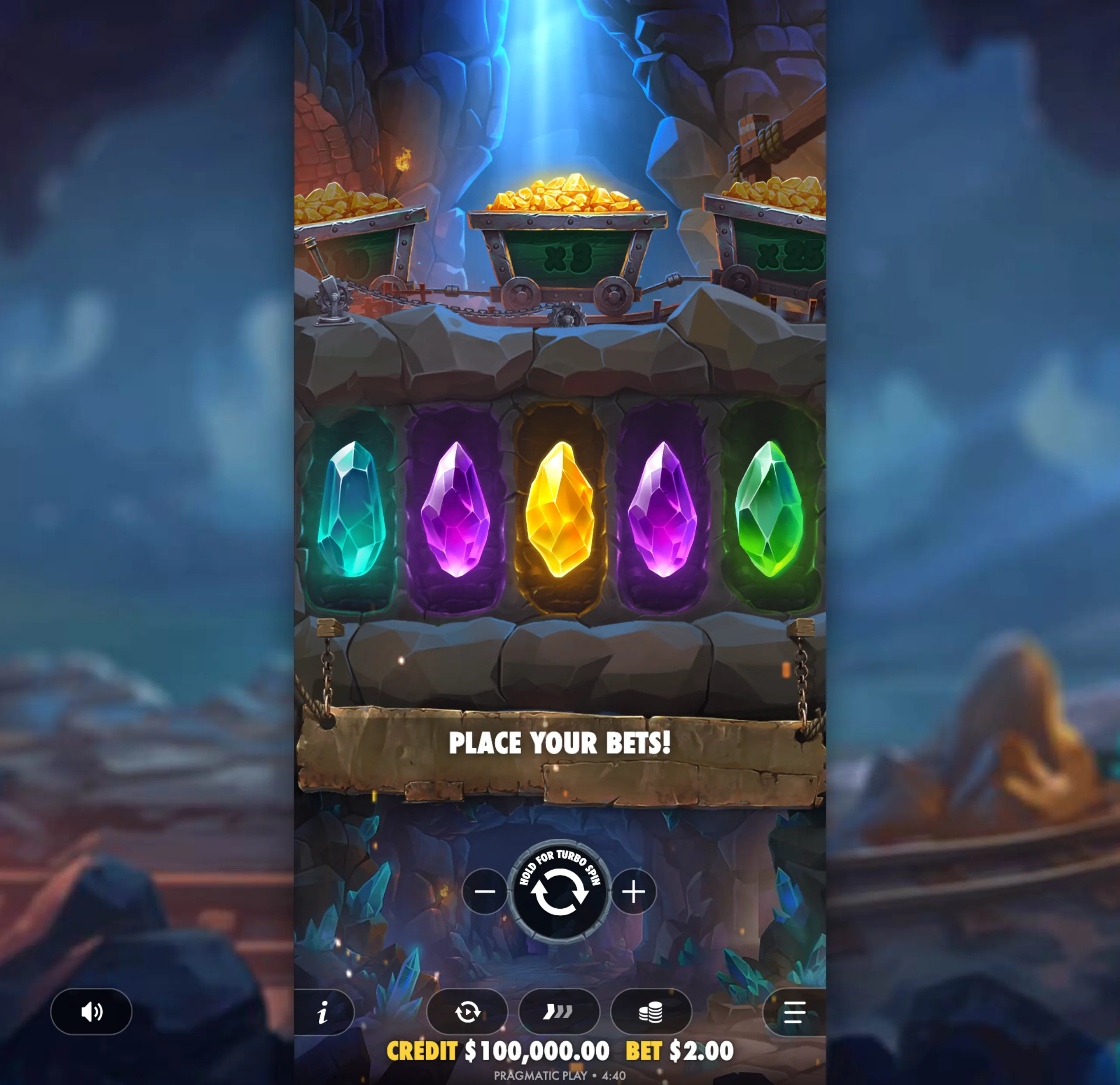 Colorful gem symbols and gold-filled mining carts in a rocky cave setting with a glowing light beam and mining equipment.